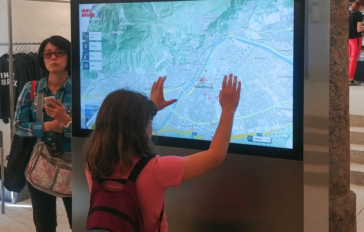 Visitor interacts with map on multitouch monitor at Innsbruck Info