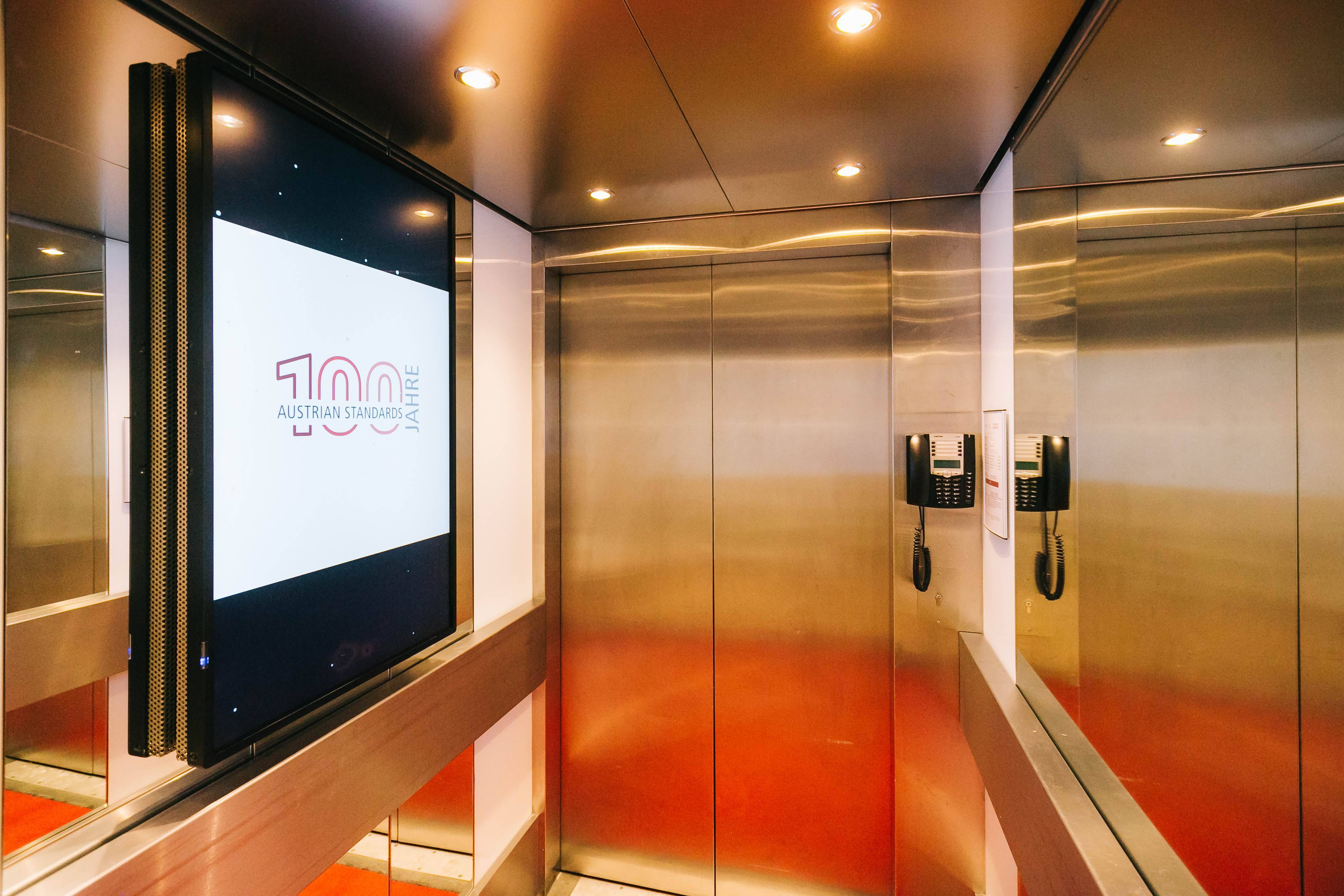 Lifts with glazed screens presenting standards and animated information