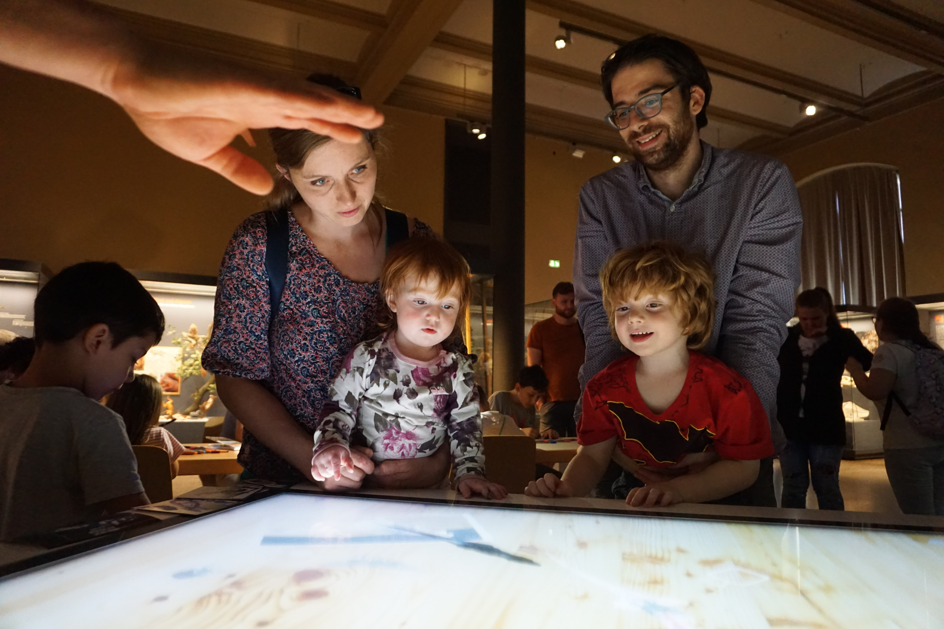 Visitors of the Natural History Museum at the interactive multitouch table with optical object recognition