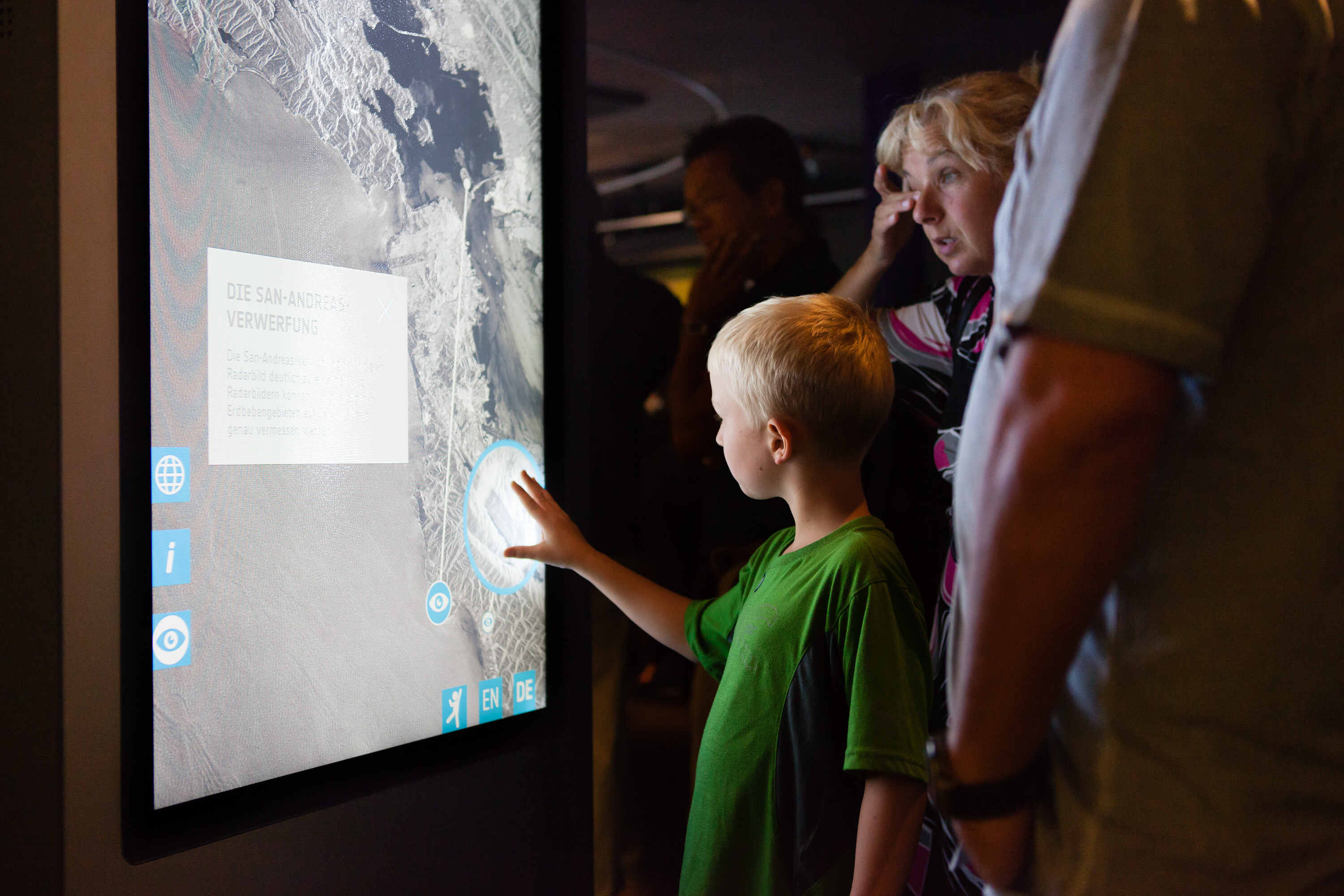 Child touching the multitouch screen of a multitouch stele in the exhibition