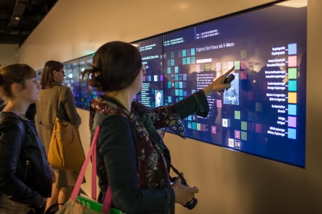 Museum visitor touches multi-touch wall in the German Spy Museum