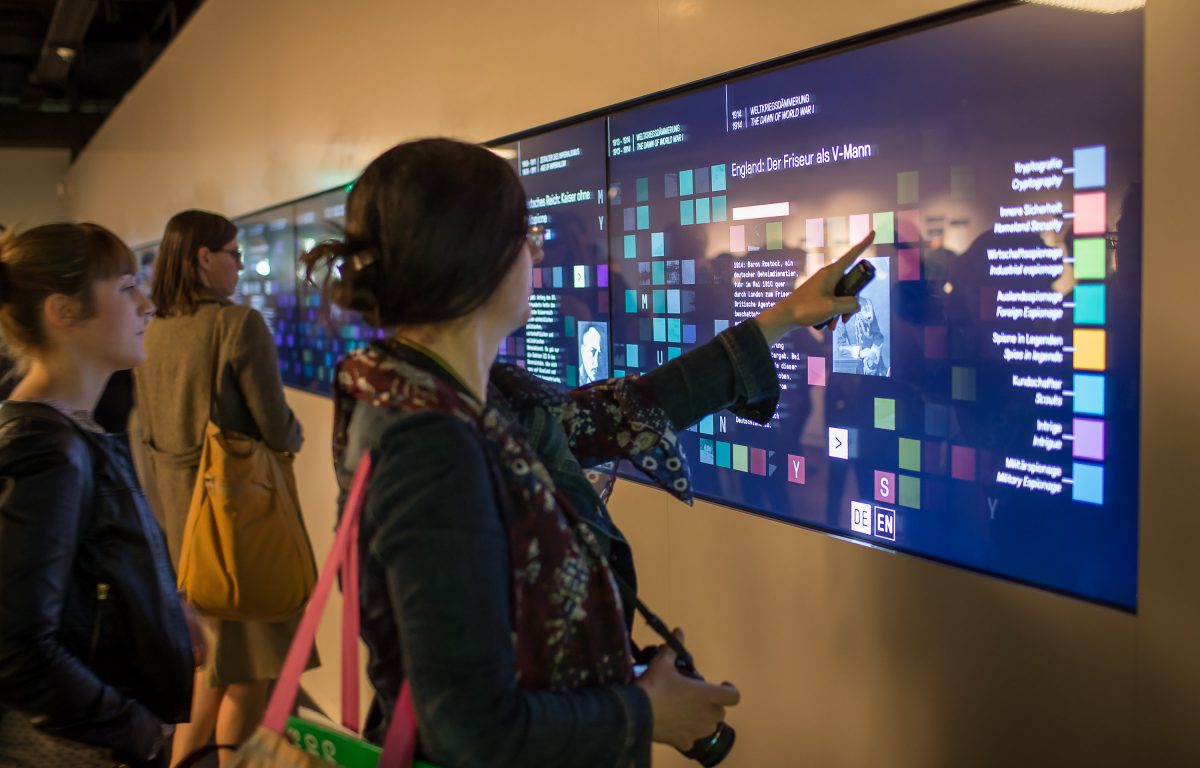 Museum visitor touches multi-touch wall in the German Spy Museum