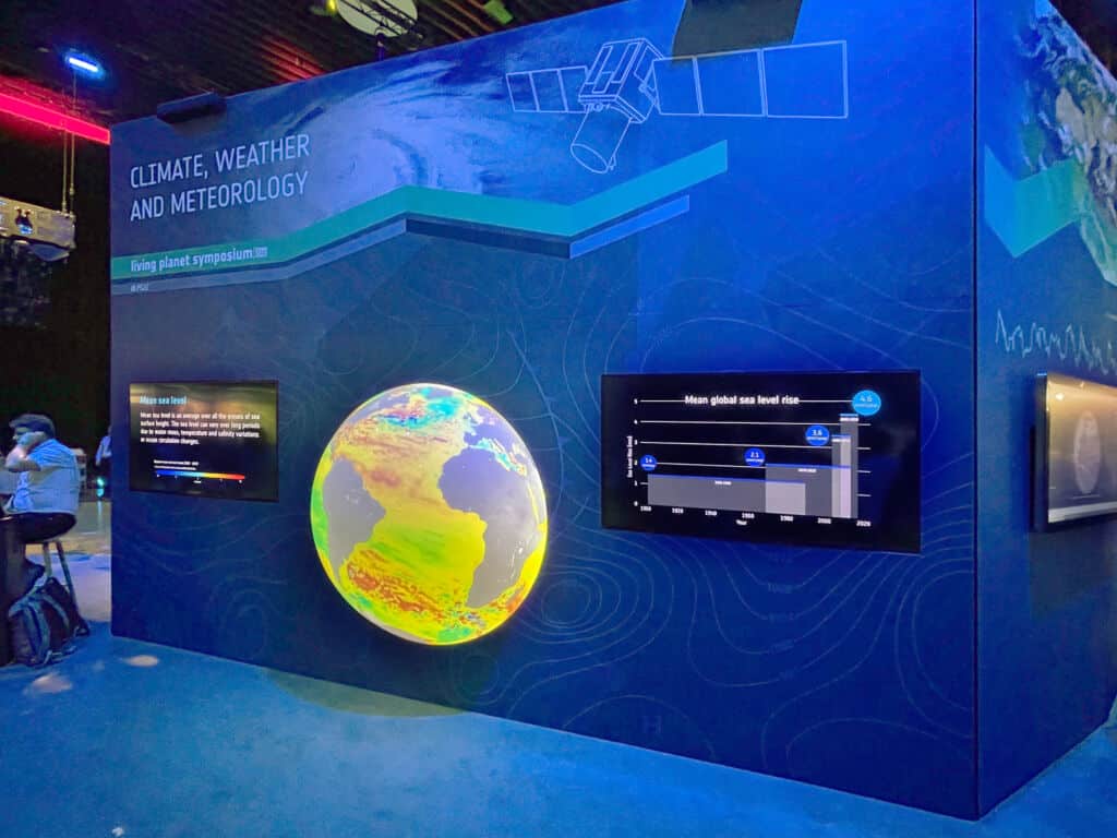 Interaktive Messewand mit 3D-Globus und integrierten Touchscreens